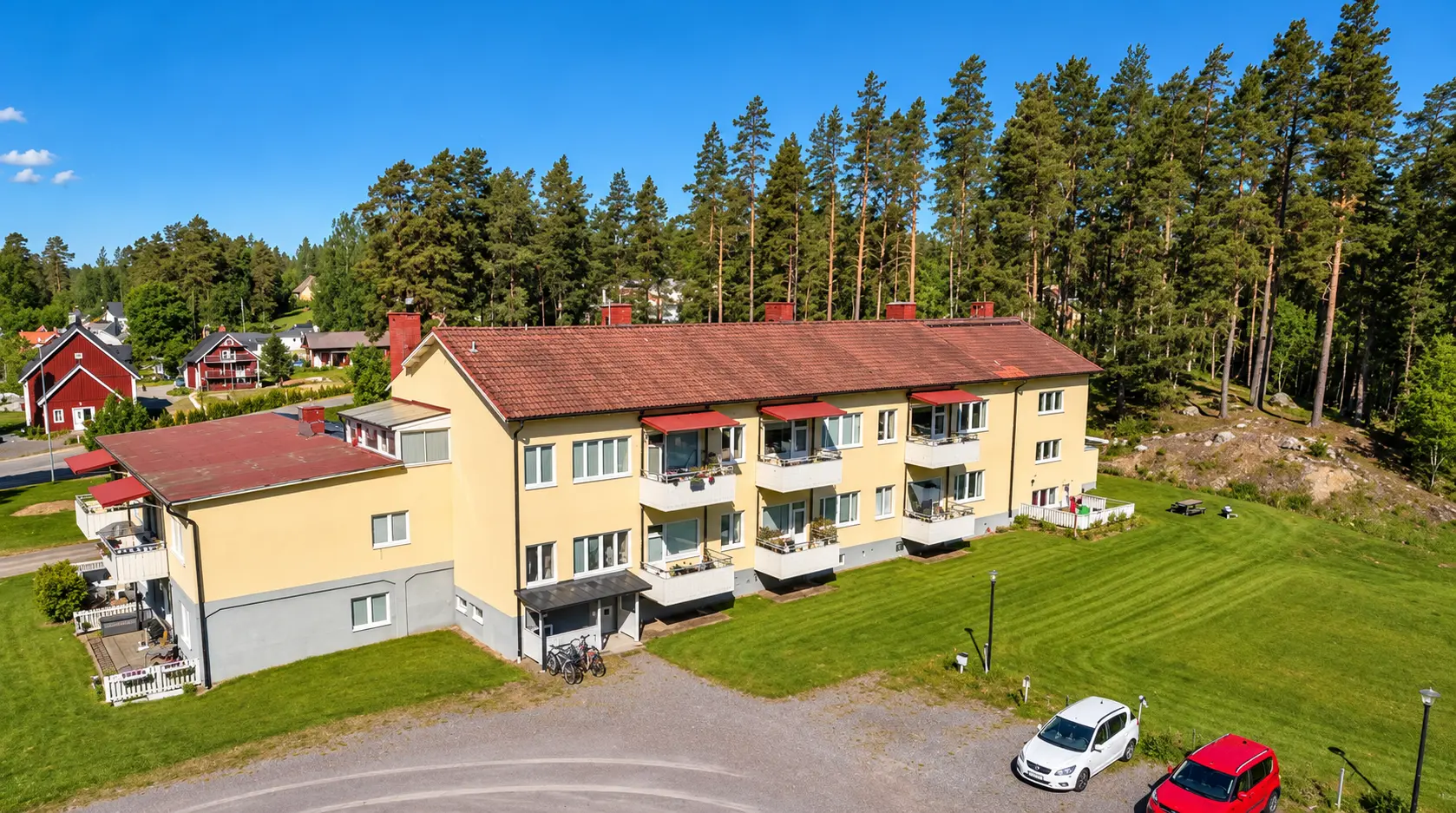 Luftbild av fastigheten på Norra Storgatan 10A–B med grusplan, gräsmatta och omgivande tallskog