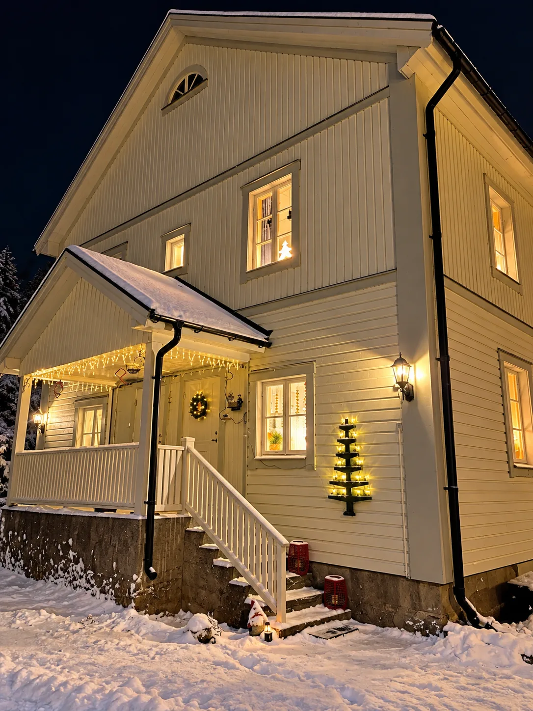 Fastighetens fasad i vinterdräkt med snö, ljusslingor och tända lyktor
