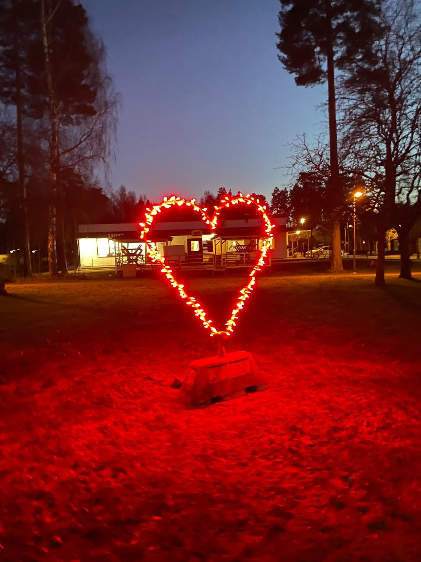 Hjärtformad ljusskulptur på gräsmattan utanför fastigheten, tänd i skymningen