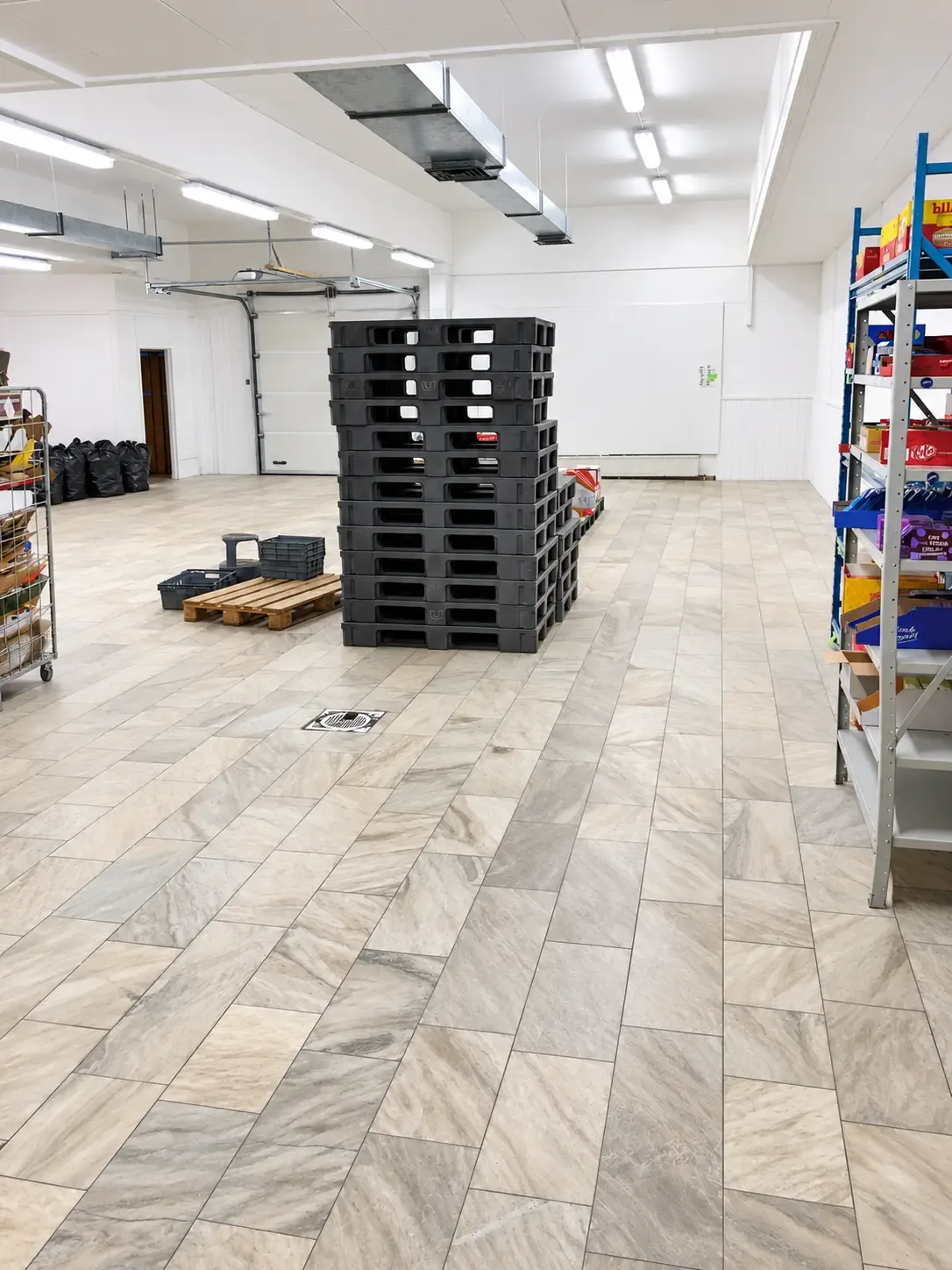 Lagerutrymme med pallar, backar, garageport och hyllor med varor