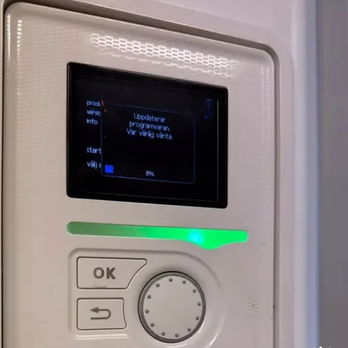 Närbild av en kontrollpanel där skärmen visar att programvaran uppdateras.